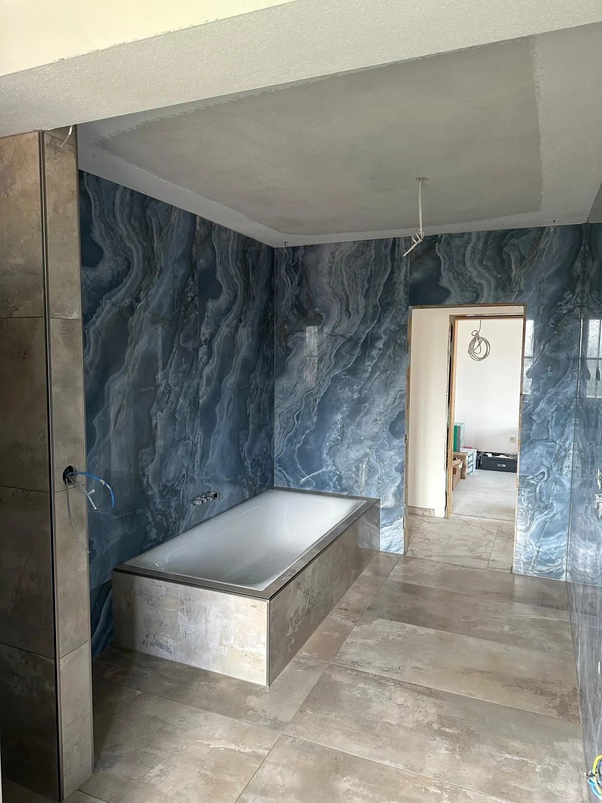 Bad mit blauen Wandfliesen in Marmoroptik und verfliester Badewanne