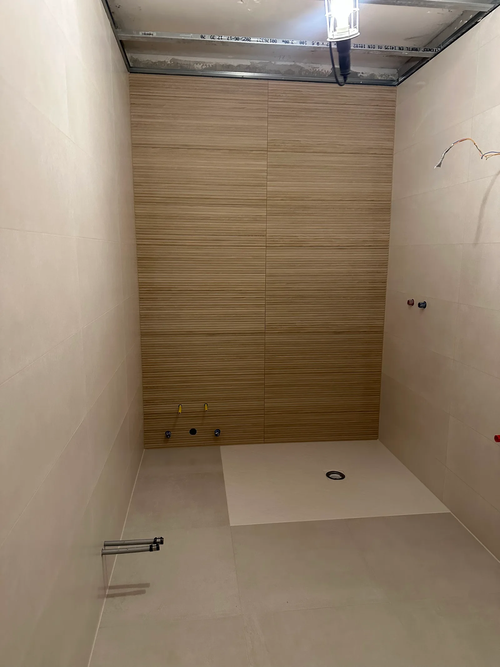 Dusche mit Wandfliesen in Holzoptik vor der Montage der Armaturen